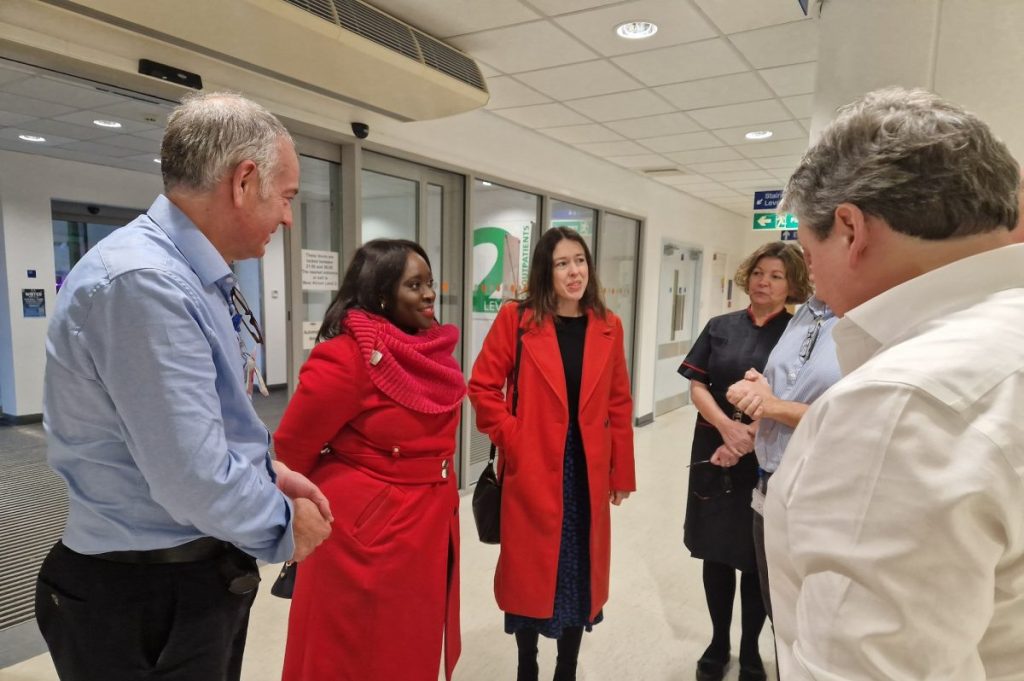 Abena and Alice hospital visit a hospital. They are wearing read coats and smiling at hospital staff.